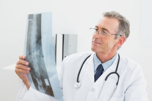 Concentrated male doctor looking at x-ray picture of spine in th